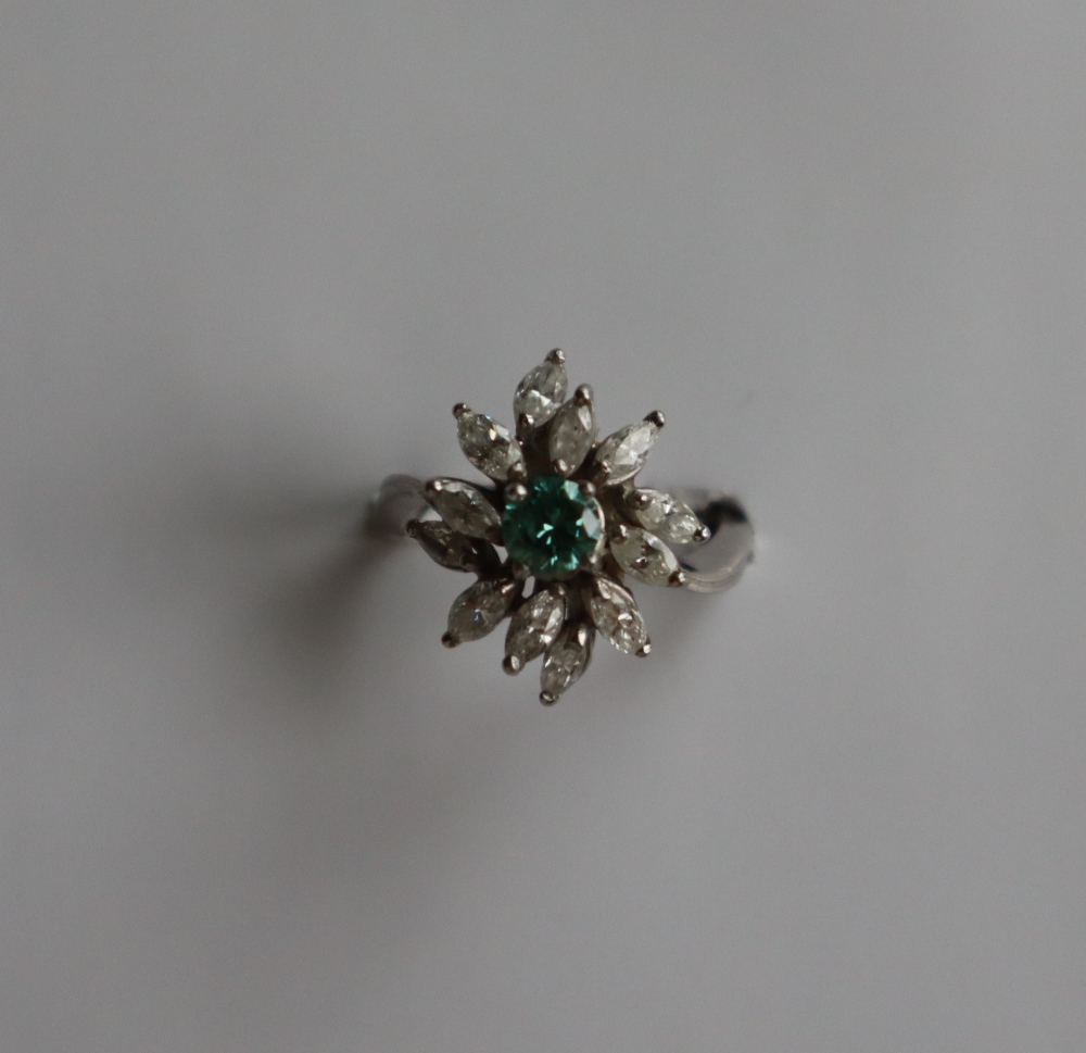 A diamond cluster ring set with a central green round brilliant cut diamond surround by Marquise