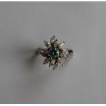 A diamond cluster ring set with a central green round brilliant cut diamond surround by Marquise