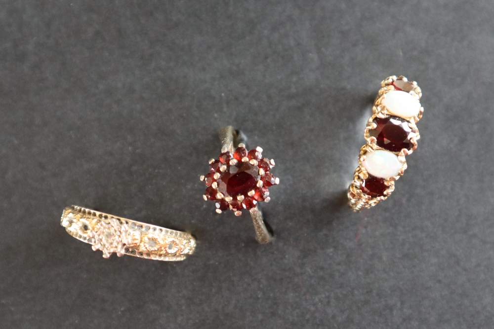 A 9ct gold dress ring set with a line of three garnets and two opals, size P 1/2,