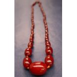 A cherry amber / bakelite beaded necklace, with graduating beads varying in size from 30mm to 10mm,
