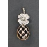 An 18ct white gold pendant with a flower shaped suspension above a diamond set egg with black