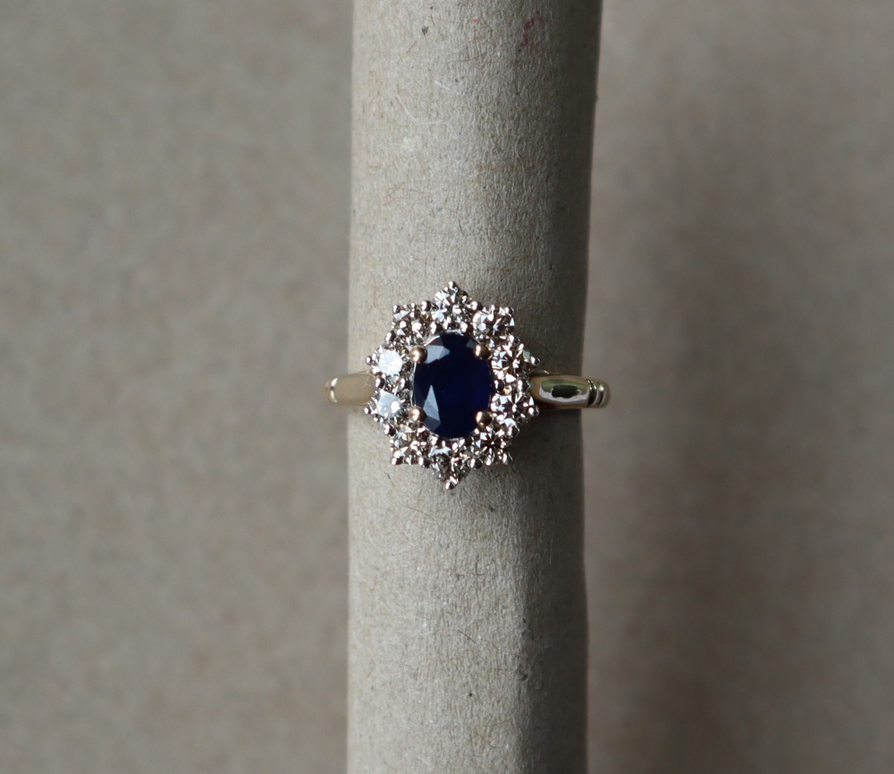 A sapphire and diamond cluster ring set with an oval faceted sapphire surrounded by round brilliant