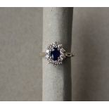 A sapphire and diamond cluster ring set with an oval faceted sapphire surrounded by round brilliant