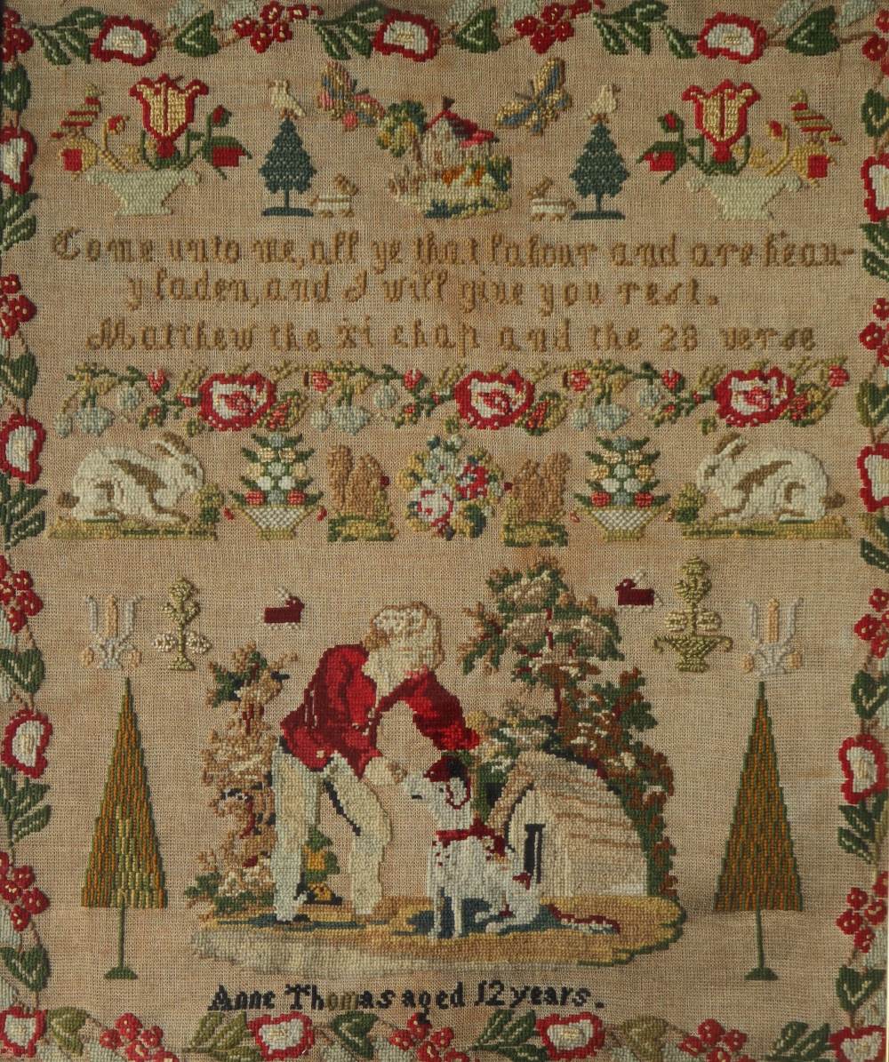 A 19th century woolwork sampler with a flower and leaf border with overall decoration of a cottage,