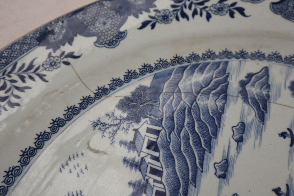 A large Chinese blue and white porcelain charger, decorated with cottages and trees on a river, - Image 2 of 5