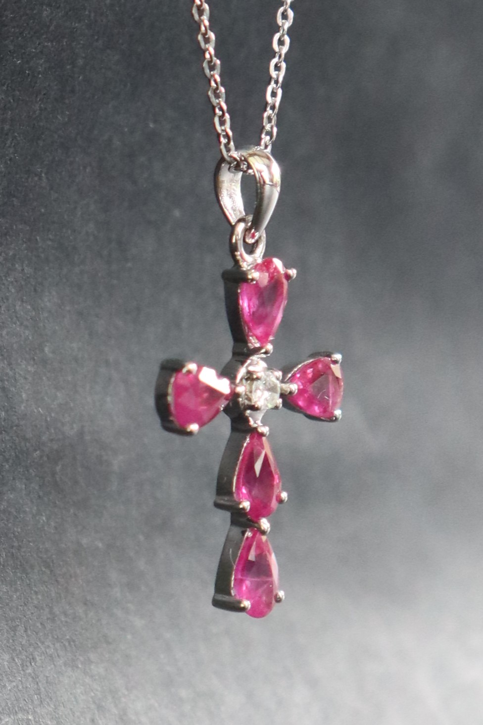 A 9ct white gold pear-shaped ruby and diamond cross on a silver chain