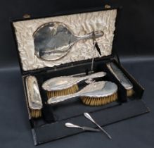 A George V silver backed dressing table set, comprising a hand mirror, a pair of hair brushes,