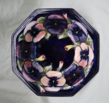 A Moorcroft pottery bowl of octagonal form, decorated with pansies to a royal blue ground,