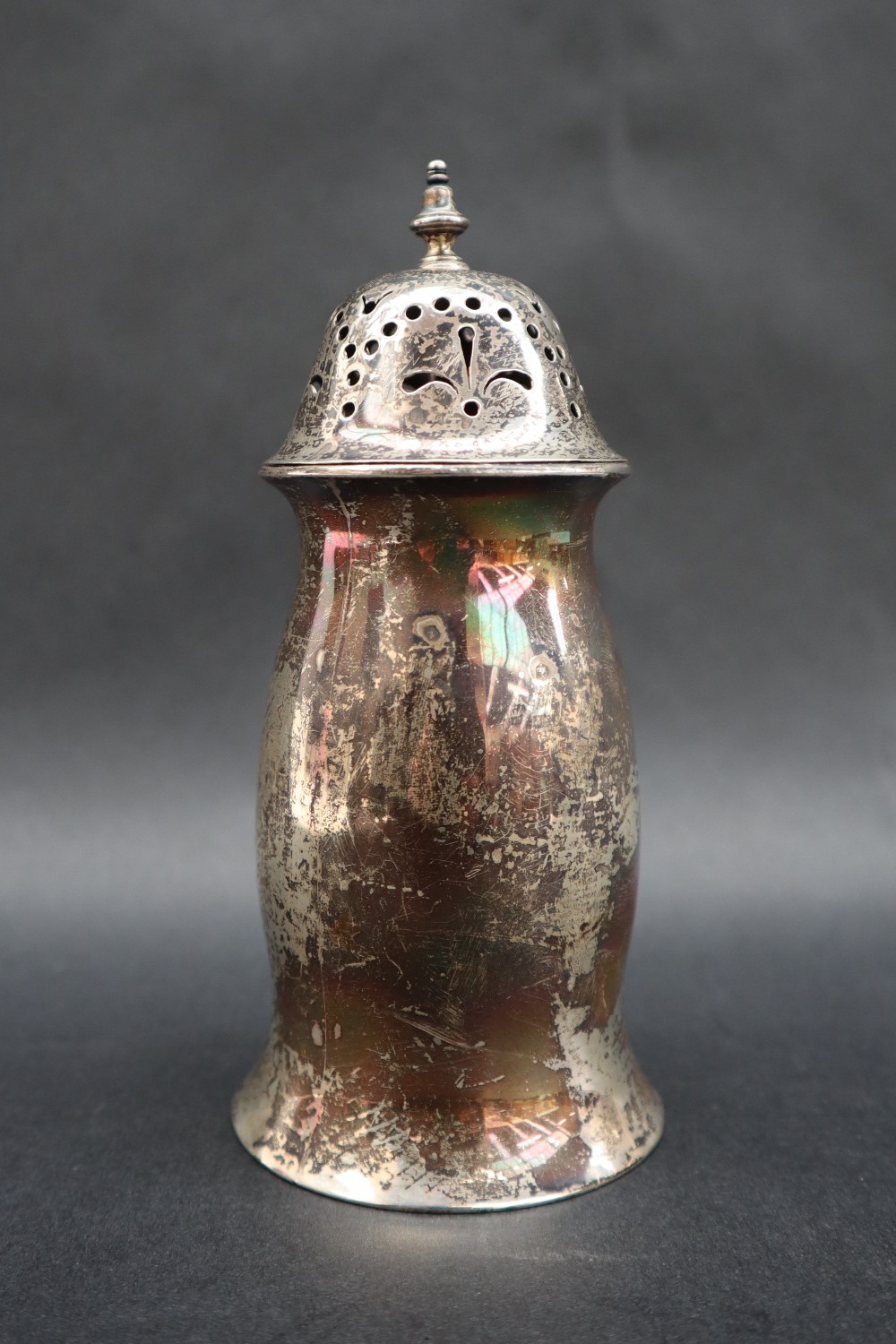 A George V silver sugar caster with a turned finial and pierced domed lid,