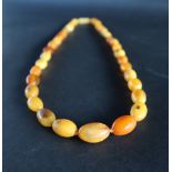 An amber bead necklace, with graduated oval beads, 63cm long,