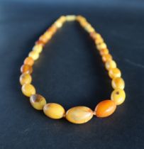 An amber bead necklace, with graduated oval beads, 63cm long,