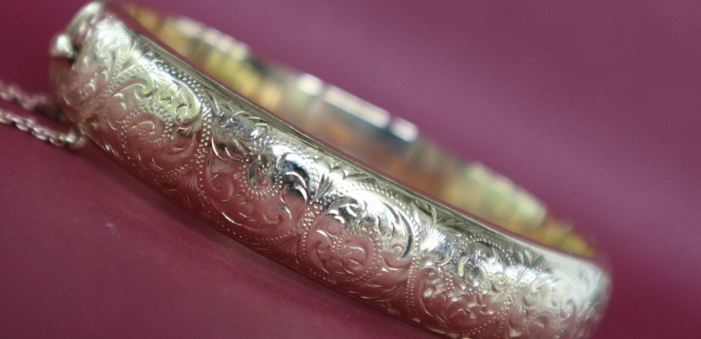 A 9ct yellow gold hinged bangle decorated with scrolls,