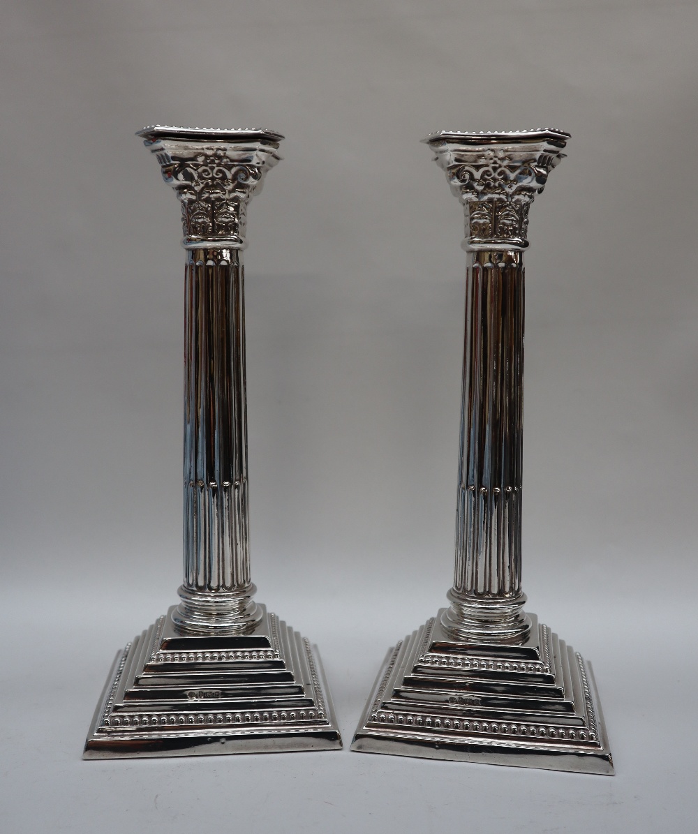 A pair of Elizabeth II silver corinthian column candlesticks with a stop fluted column and stepped