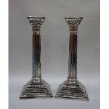 A pair of Elizabeth II silver corinthian column candlesticks with a stop fluted column and stepped