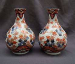 A pair of Japanese Imari pattern vases with a flared neck and tapering body,