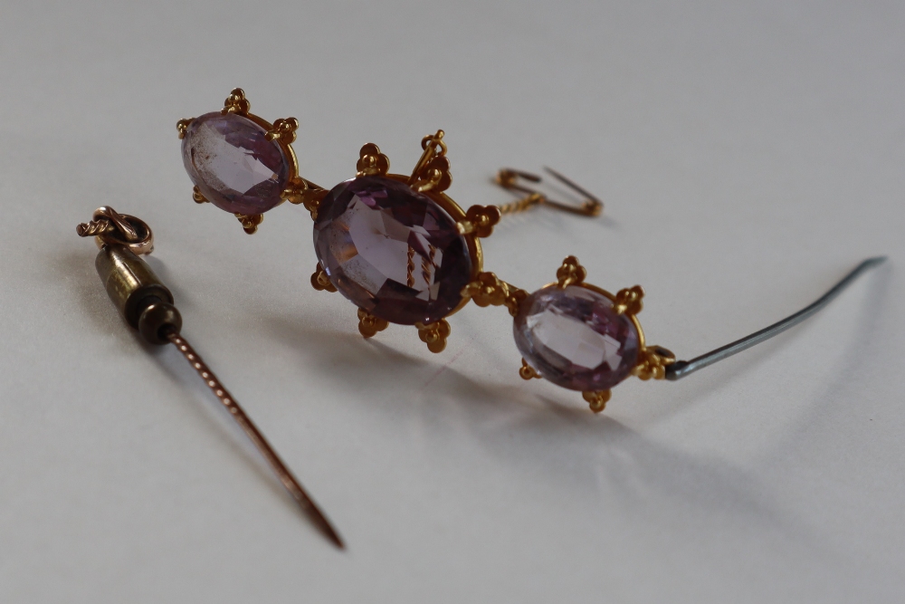 An amethyst brooch set with three oval faceted amethysts to a yellow metal setting, 6cm long, - Image 2 of 3
