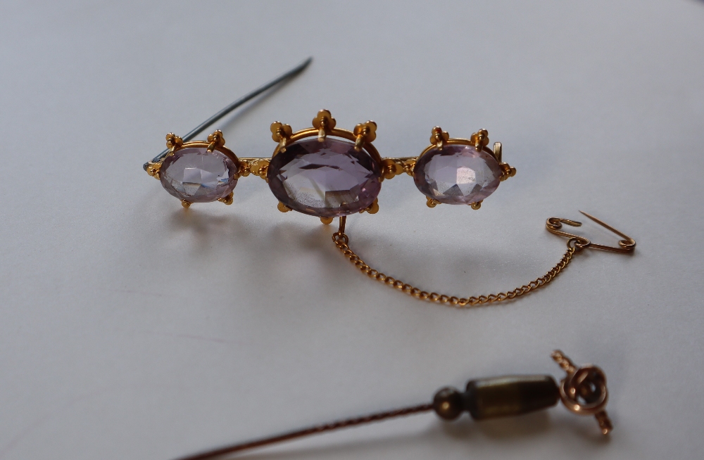 An amethyst brooch set with three oval faceted amethysts to a yellow metal setting, 6cm long,