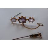 An amethyst brooch set with three oval faceted amethysts to a yellow metal setting, 6cm long,