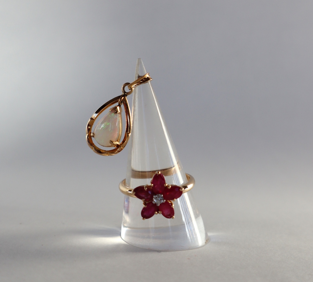 A ruby and diamond floral ring set with a central round old cut diamonds and five radiating oval