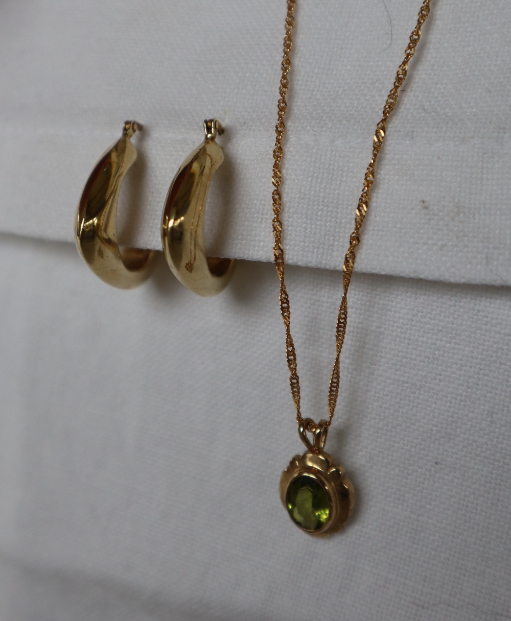 A pair of 9ct gold hoop earrings together with a 9ct gold peridot set pendant on a 9ct gold chain,