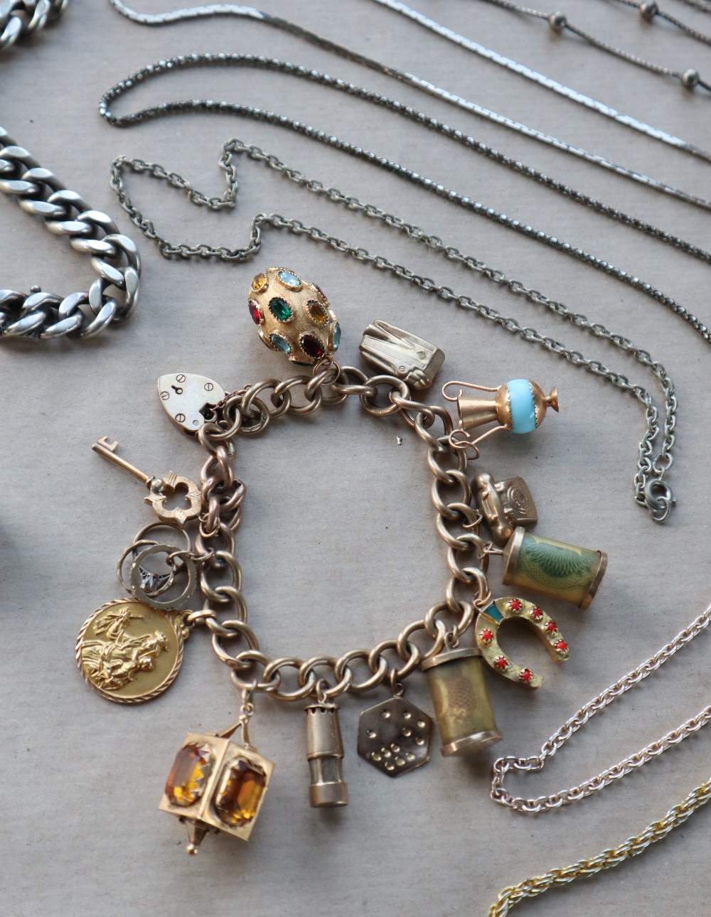 A 9ct yellow gold bracelet set with numerous charms including a lighter, telephone, miners lamp, St.