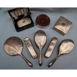 A George V silver backed part dressing table set including a hand mirror,