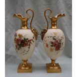 A pair of Royal Worcester porcelain ewers with wavy spout, mask terminal handles,