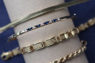 A 9ct gold sapphire and diamond bangle set with four oval faceted sapphires and five round