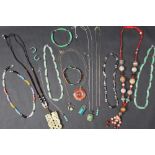 A carved jade pendant on a string necklace together with other jade necklaces, bracelets,