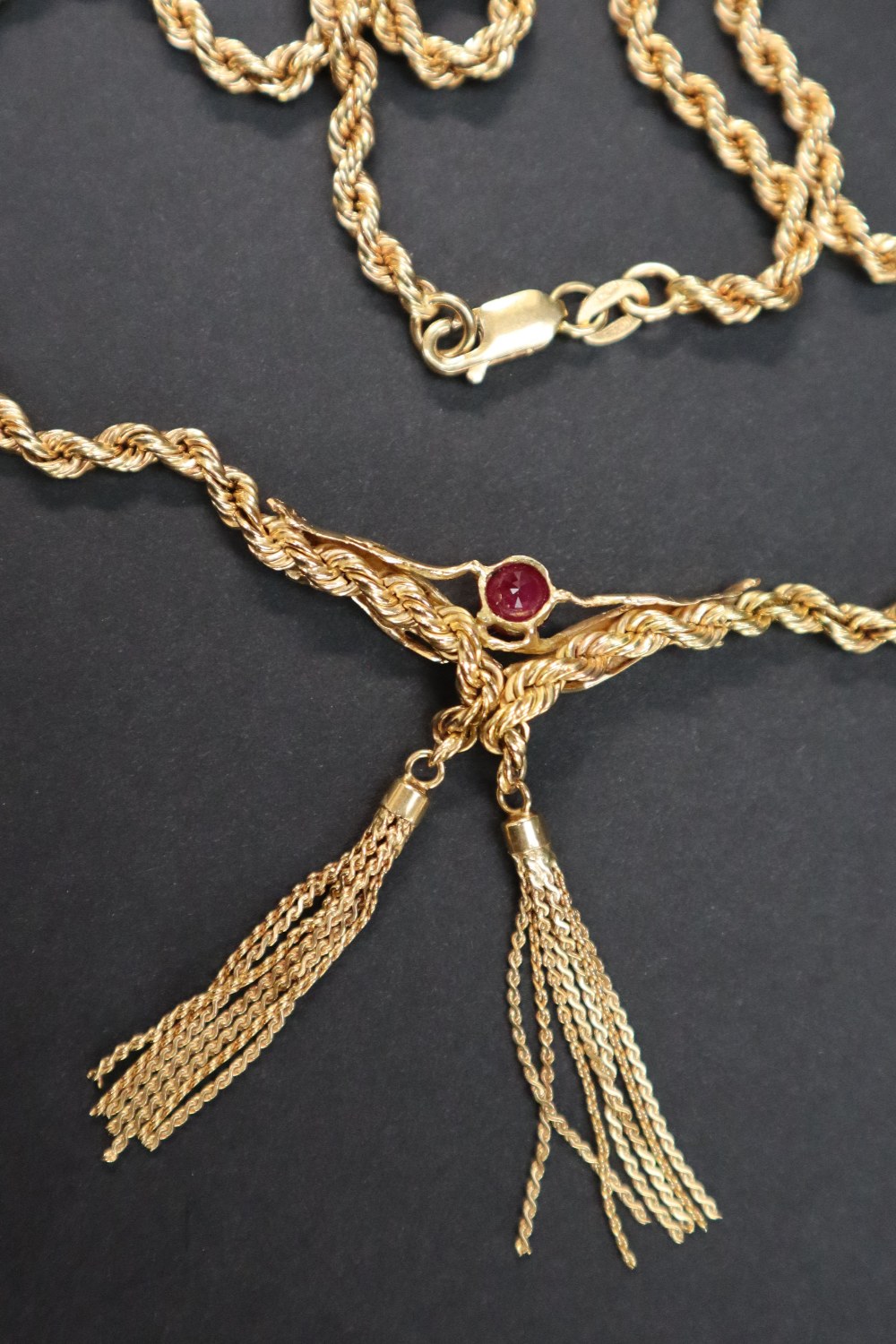 An 18ct yellow gold rope twist necklace, set with a ruby held between hands with tassels underneath, - Image 4 of 4