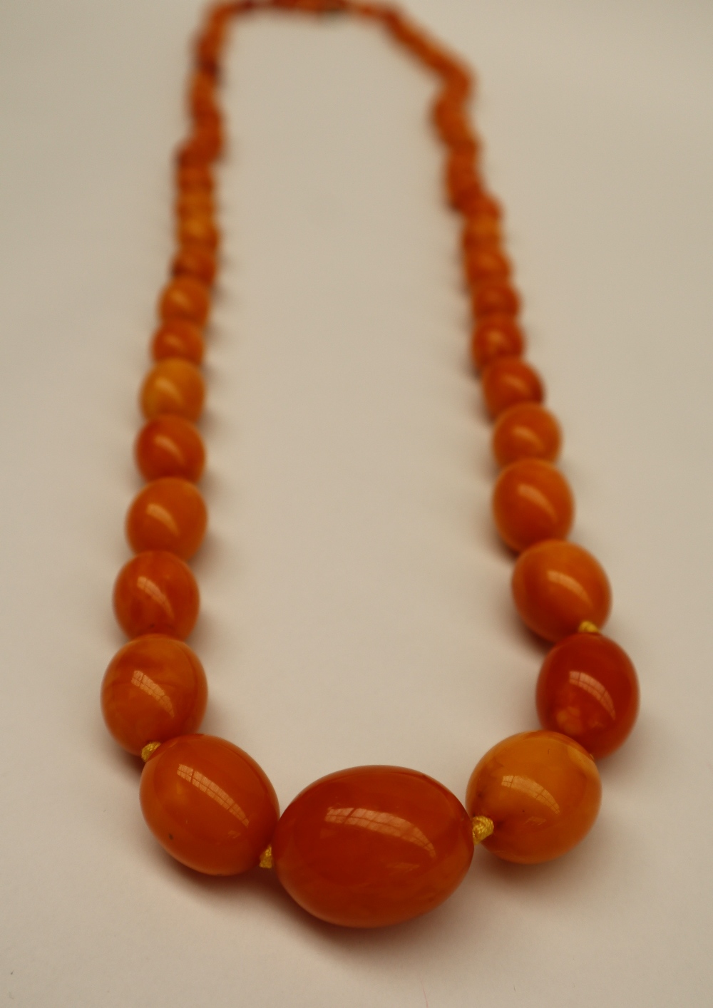 An amber bead necklace set with fifty eight graduated beads varying in size from 25mm to 6mm,