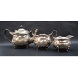 A George V silver three piece tea service with a gadrooned edge and bulbous body on four feet,