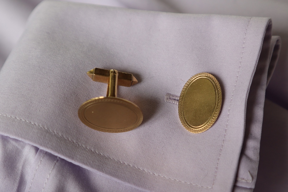 A pair of 9ct yellow gold cufflinks of oval form with engine turned decoration on a post and swivel,