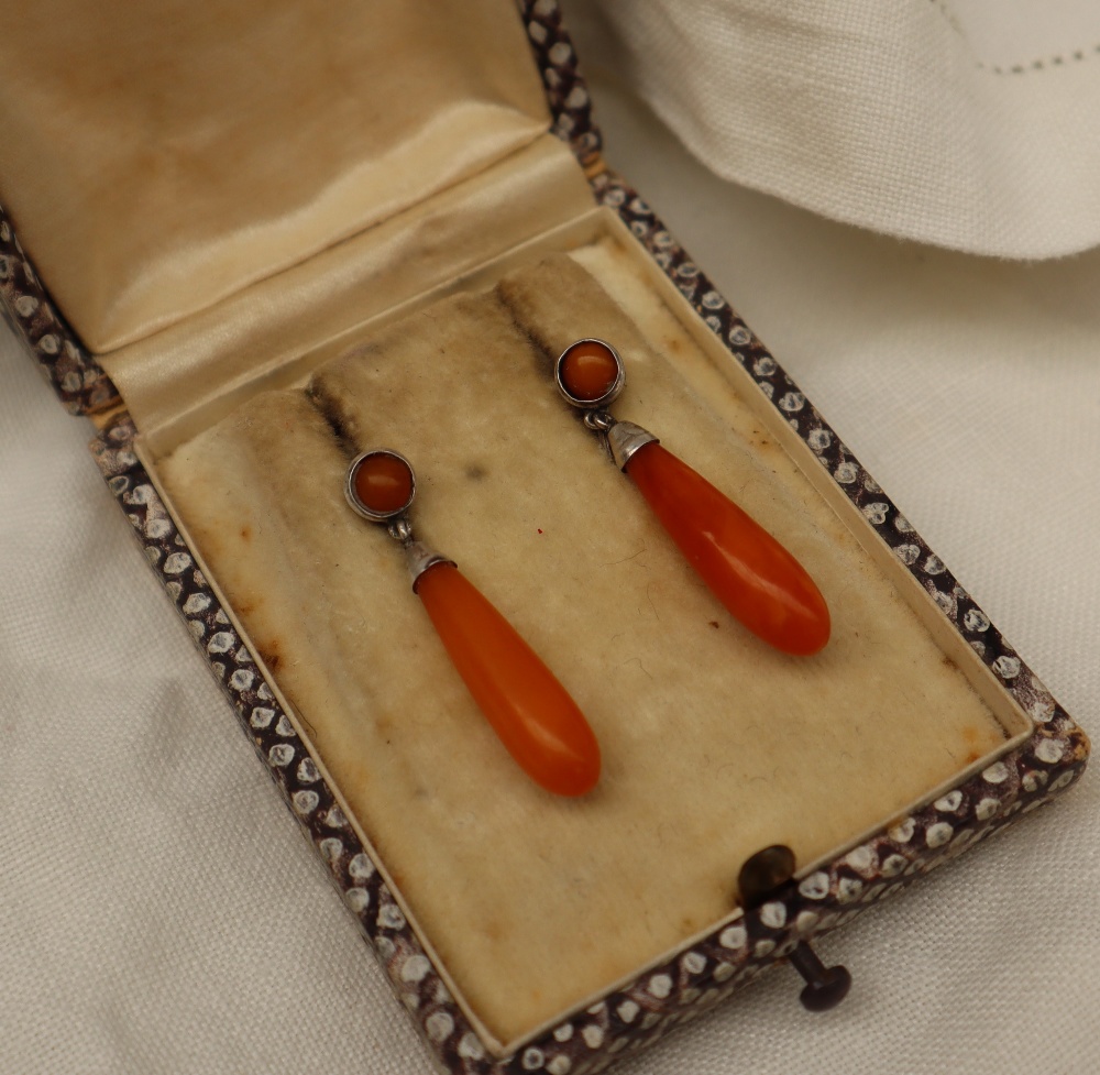 A pair of amber drop earrings, mounted in white metal,