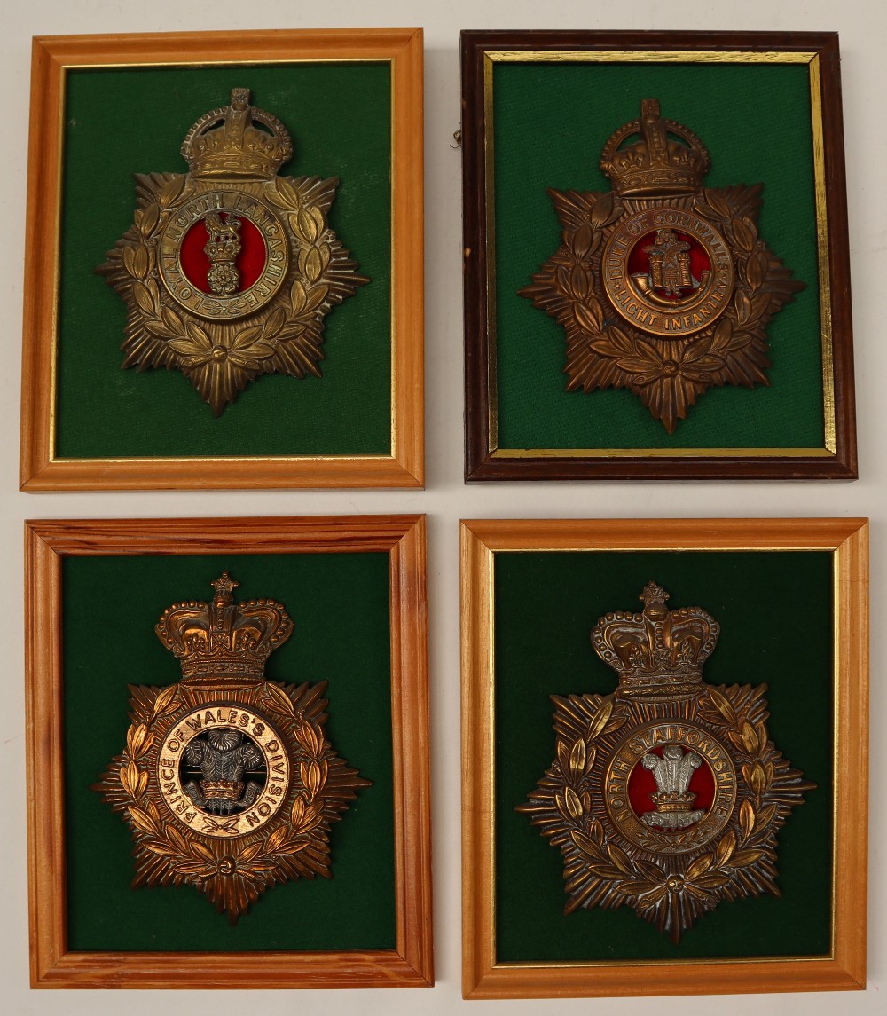 A collection of four reproduction brass military helmet plates including North Staffordshire,