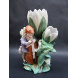 A continental porcelain triple lily vase moulded with a bearded sprite playing a cello with the