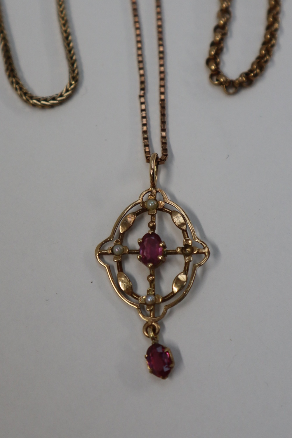 A 9ct gold ruby and seed pearl pendant on a 9ct gold chain together with 9ct gold necklaces,
