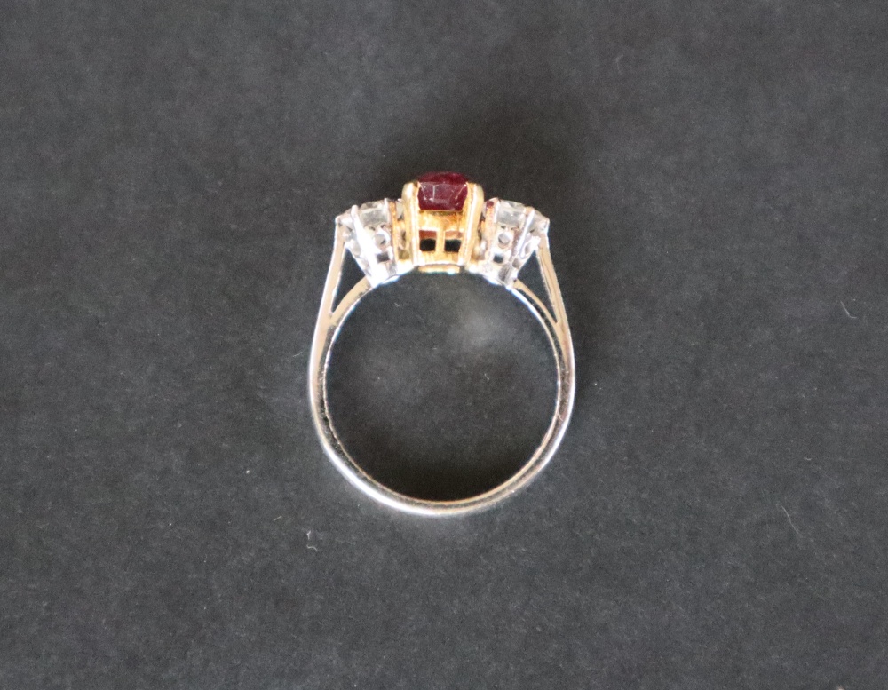 A ruby and diamond ring set with a central oval faceted ruby, approximately 9mm x 6mm, - Image 11 of 12