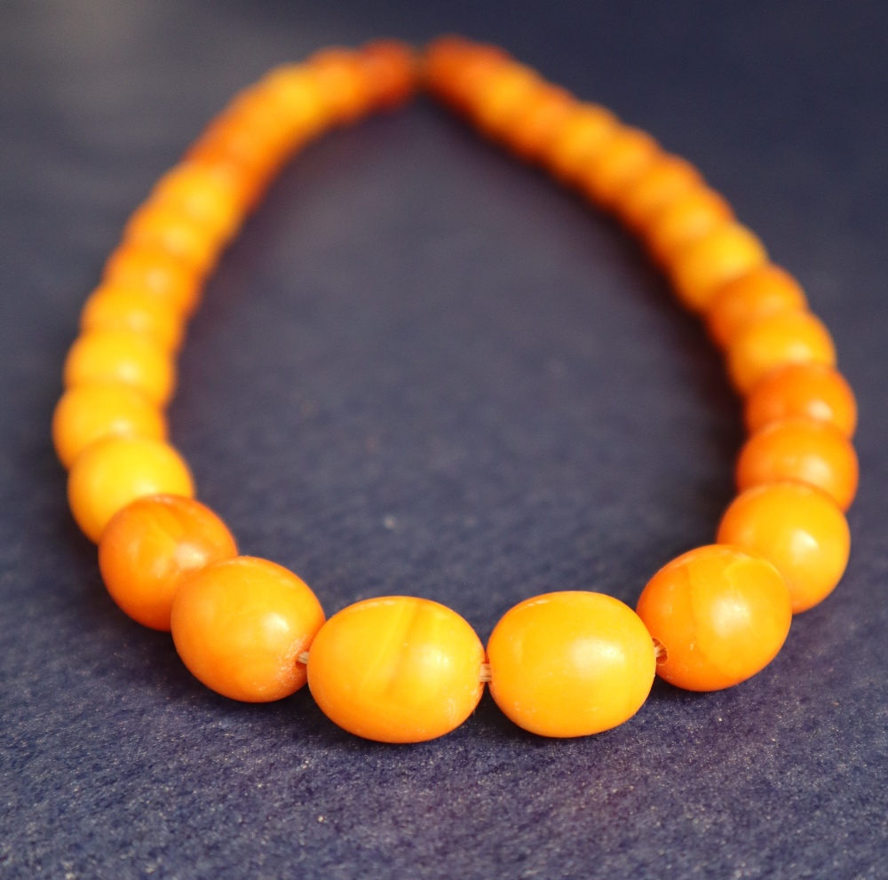 An amber bead necklace with graduated oval beads varying in size from 15mm to 10mm, 42cm long,