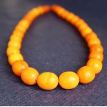 An amber bead necklace with graduated oval beads varying in size from 15mm to 10mm, 42cm long,
