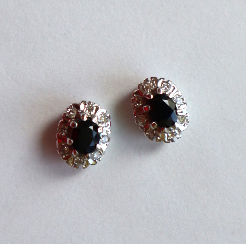 A pair of sapphire and diamond cluster earrings, each set with an oval cut sapphire approximately 0.