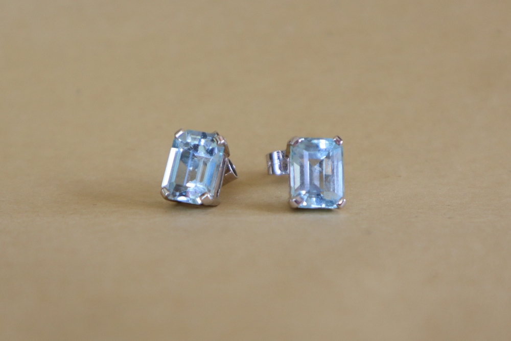 A pair of topaz single stud earrings each emerald cut approximately 2cts to a white metal setting