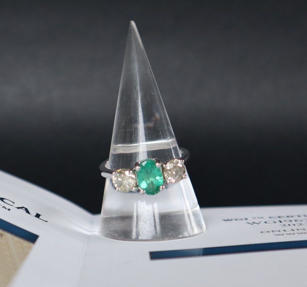 An 18ct white gold emerald and diamond trilogy ring set with an oval faceted emerald approximately