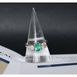 An 18ct white gold emerald and diamond trilogy ring set with an oval faceted emerald approximately