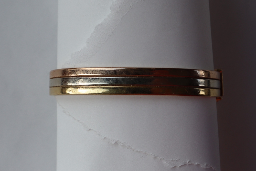 An 18ct three colour banded gold hinged bangle,