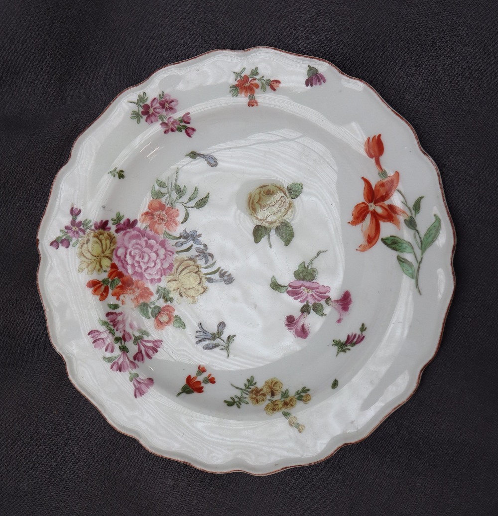 A porcelain plate with a shaped edge, painted with sprays of garden flowers,