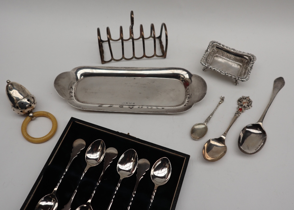 A set of six George V cased silver coffee spoons, Birmingham, 1925 together with a rattle,