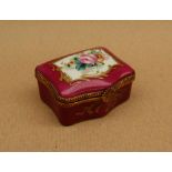 A 19th century porcelain box and cover painted with flowers to the lid and a rose pink border with