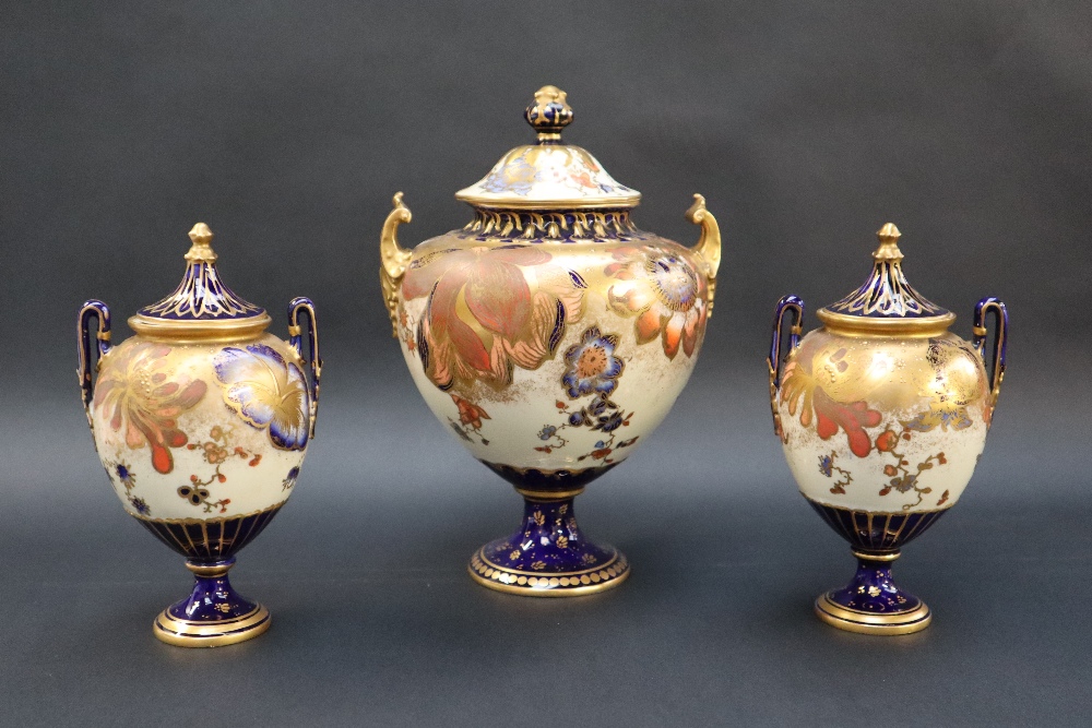 A Royal Crown Derby garniture of three vases with domed covers the body decorated with flower heads