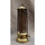 A brass Davy Miners lamp with a domed brass top and mesh screen, with glass interior,